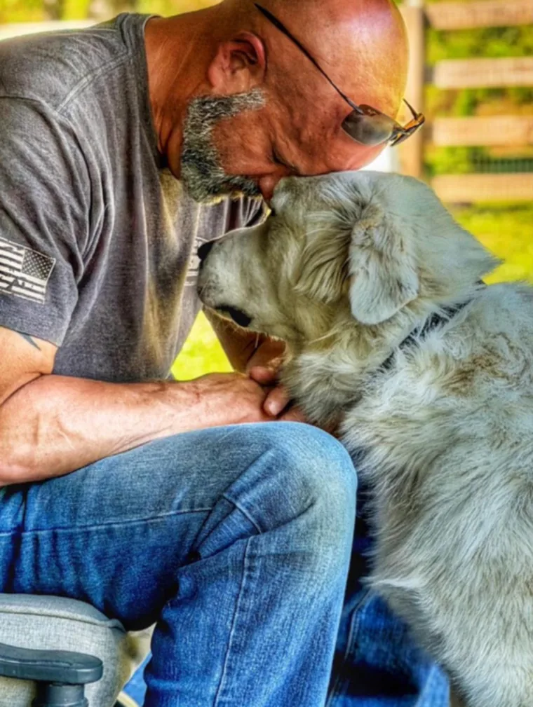 A trainer resting his head against a scruffy dog he is working with