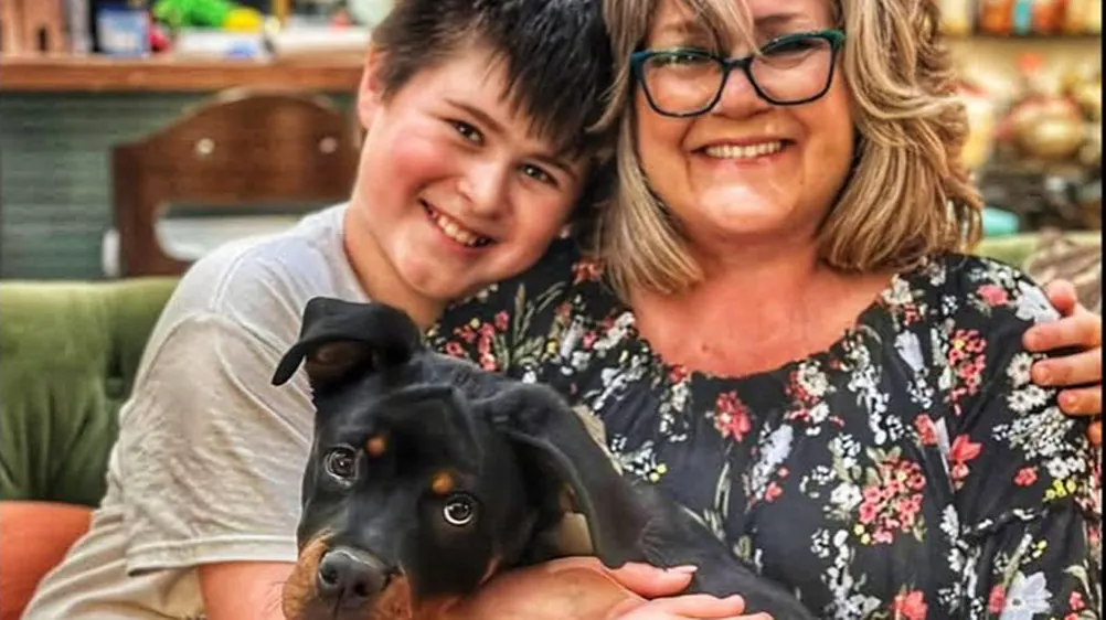 A mother and son holding their puppy at home