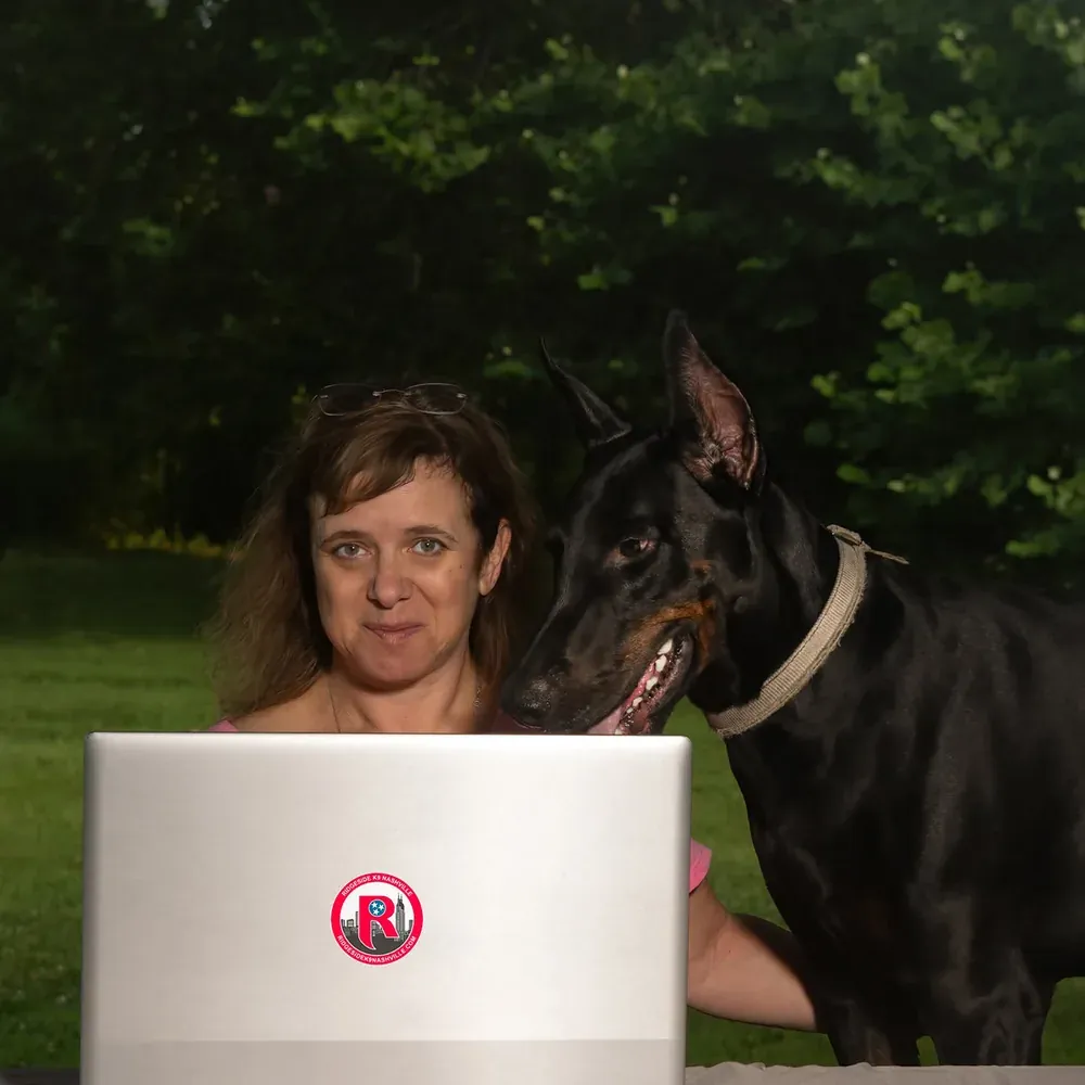 Judy Barth at her desk with a Doberman beside her